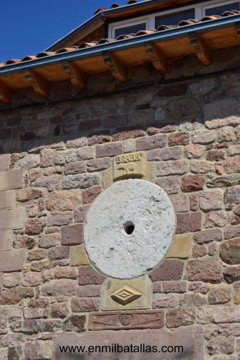 Detalle de una piedra de molino en una fachada de Brañosera