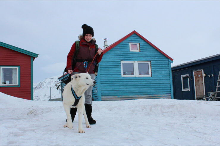 Mujer joven con perro en paisaje nevado