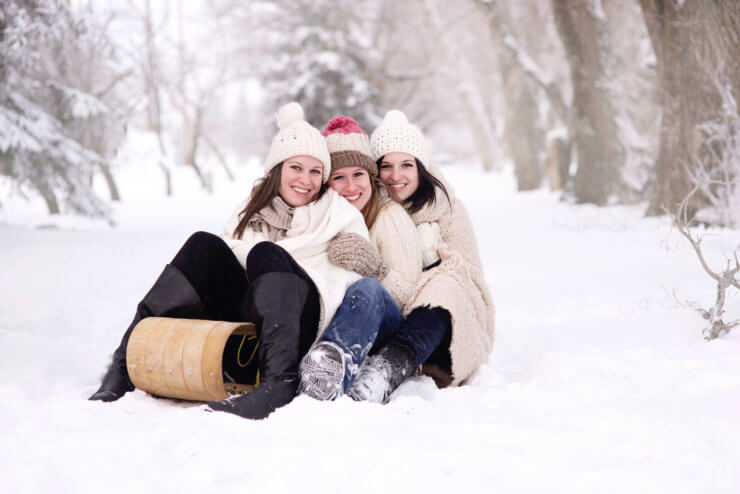 3 mujeres jovenes disfrutando del invierno y la nieve en un trineo